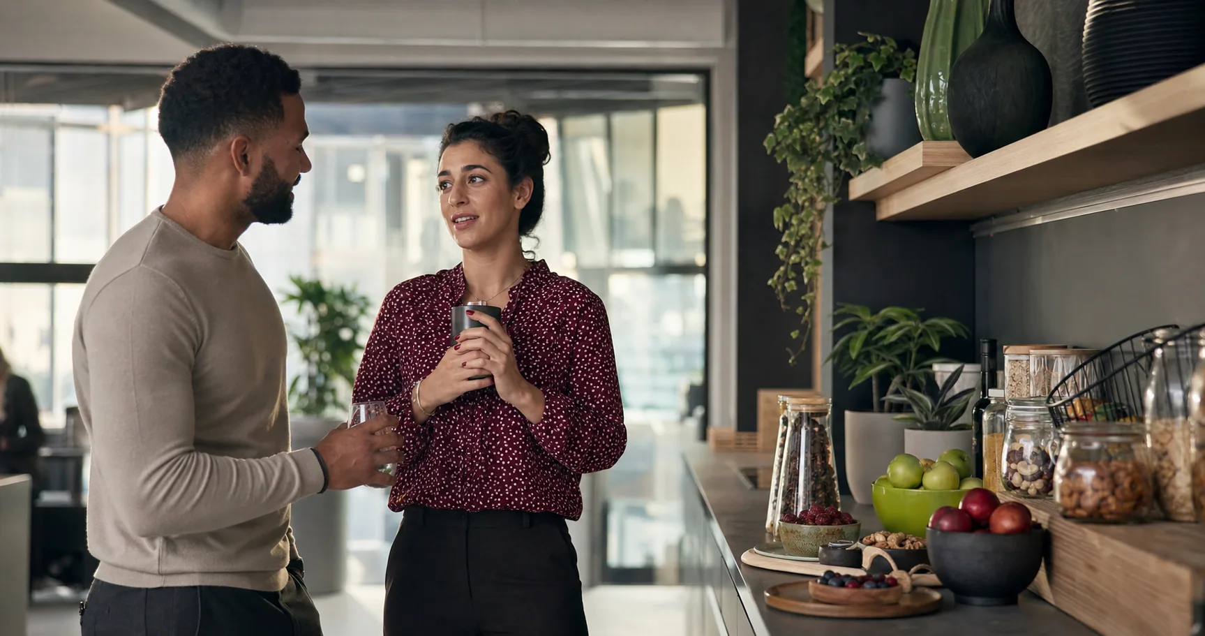 Two colleagues enjoying a break beside a well-stocked office pantry